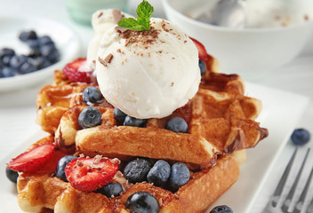 Delicious waffles with berries and ice cream on plate, closeup