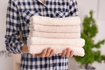 Woman holding stack of clean soft towels at home