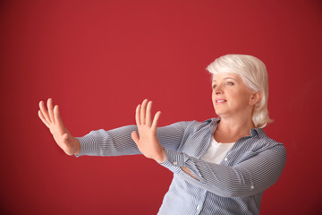 Portrait of mature woman rejecting something on color background