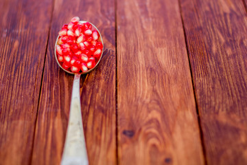Pomegranate seeds, red, lie on a wooden vintage background