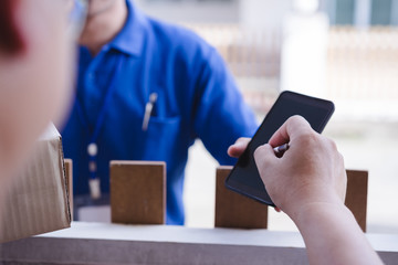 Young man signing on smartphone from delivery man after receiving parcel from courier at home. Delivery service concept