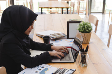 Young muslim business woman wearing black hijab,working at coworking. - obrazy, fototapety, plakaty