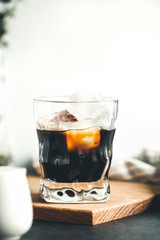 Iced coffee espresso with iced cubes in a glass in a modern kitchen against white background. Copy space.