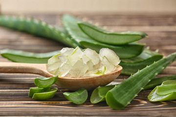 Spoon with aloe vera on wooden table