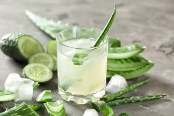 Glass of aloe vera juice on grey table