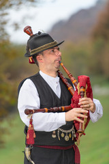 Typical player in traditional northern Italy bagpipe costume, an alpine valley of Bergamo