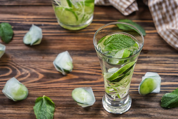 Glass of fresh cucumber water on wooden table