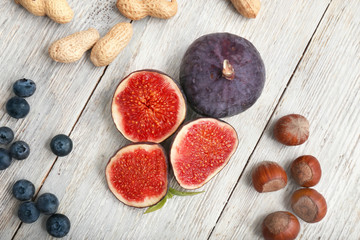 Fresh ripe figs with nuts and blueberries on wooden table