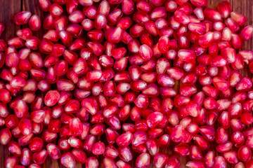Pomegranate seeds, red, lie on a wooden vintage background