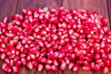 Pomegranate seeds, red, lie on a wooden vintage background