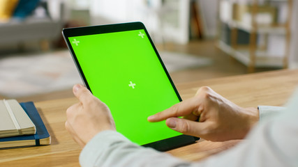 Man Using Hand Gestures on Green Mock-up Screen Digital Tablet Computer in Portrait Mode while...
