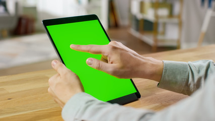 Man Using Hand Gestures on Green Mock-up Screen Digital Tablet Computer in Portrait Mode while...