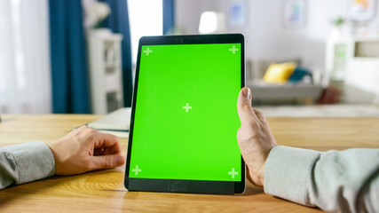 Close-up of Man Using Green Mock-up Screen Digital Tablet Computer in Portrait Mode while Sitting...