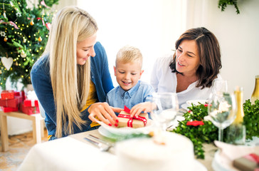 A small boy with present and mother and grandmother at home at Christmas time.