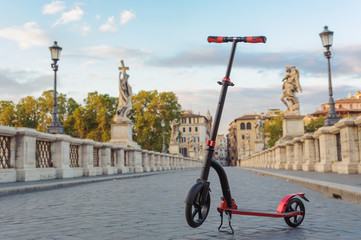 Red push scooters against the backdrop of the Ponte Sant Angelo in the Roma, Italy. Horizontal.