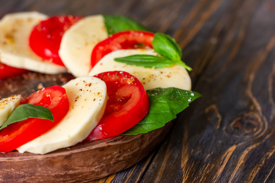 Caprese salad with mozzarella on a light wooden background, close up