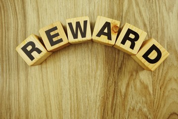 reward word in wooden cube alphabet letters top view on wooden background