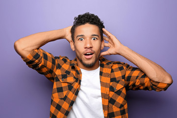 Portrait of shocked African-American man on color background