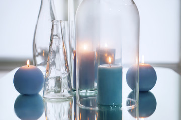 Glassware with beautiful burning candles on table with reflection