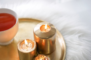 Beautiful burning candles with cup of aromatic tea on metal tray