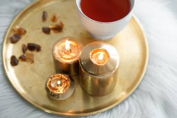Beautiful burning candles with cup of aromatic tea on metal tray