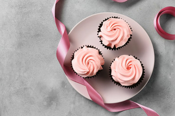 Plate with tasty cupcakes on grey table