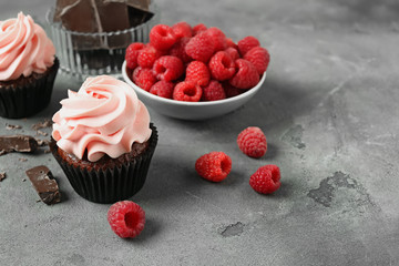 Sweet cupcakes, raspberry and chocolate on grey table