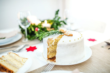 White a cake on table set for dinner at Christmas time.