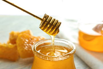 Honey dripping from dipper into glass jar, closeup