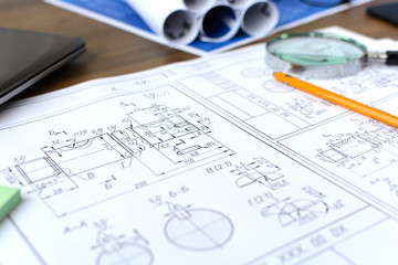 Business accessories (laptop, smartphone, pens, magnifier), accessories for drawing (plans, rulers) and learning on the table