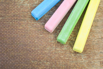Colored chalk sticks on old wood board as copy space background