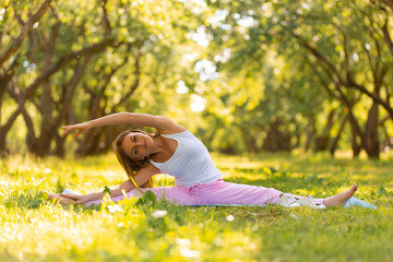 Beautiful girl doing yoga in the park. Stretching exercises