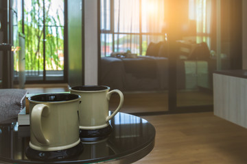 Twin white coffee or tea cup put on black table in comfortable room with sunrise lighting and copy space.