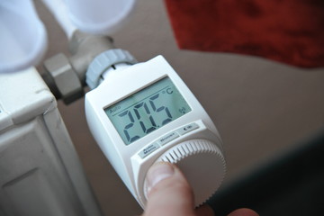 hand dreht an elektronischen vernetzten heizungsthermostat an heizung
