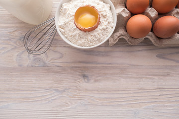 Flat lay of Ingredients for baking. Flour, eggs, milk, yolk on a table. Sweet pastry baking concept.  Top view