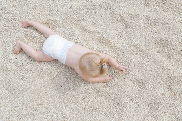 Adorable cheerful baby crawling on the pebble beach