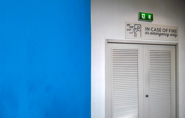 Emergency or fire exit gate with blurred dirty blue wall and copy space