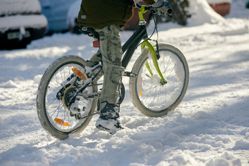 Closeup of young boy with bicycle on snow cover road