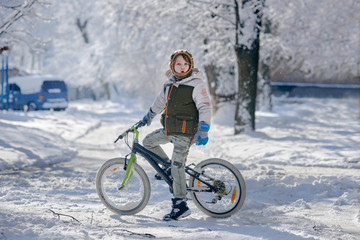 Active young happy boy on bicycle in winter city