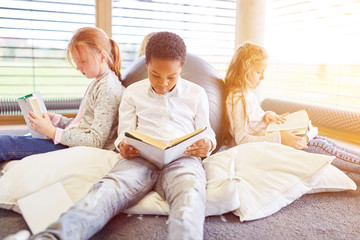 Gruppe Kinder lesen in Leseecke einer Bibliothek