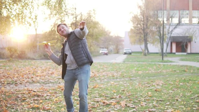 A man throws up a toy airplane. Autumn Park
