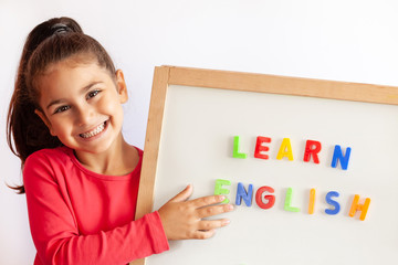 Language education concept. Learn English. Do you speak English. Cute little child girl with colored letters on the blackboard. English language school. English for children.