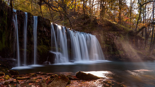 Waterfall Ddwli Uchaf near pontneddfechan in the brecon beacons national park, Wales. It is autumn, and golden leaves are all around.  Long shutter speed for a smooth effect on the water