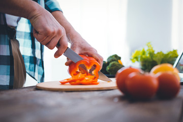 Equal slices. Close up of a nice handsome man cutting pepper into equal slices