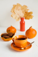 Autumn breakfast.Orange cup of black tea on white
