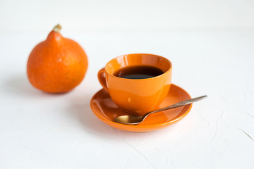 Autumn breakfast.Orange cup of black tea on white
