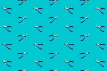 Fototapeta premium Pliers with blue handles pattern on a green background, flat lay. Pop view