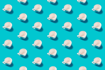 White cups pattern on a blue background flat lay. Top view. Concept.