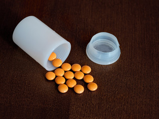 Scattered on the table orange pills, overturned jar
