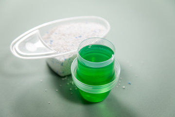 Waschmittel Pulver und grünes Flüssig Gel in Dosierung Messbecher